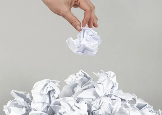 Ręka trzymająca zgniecioną kartkę papieru jako symbol odejścia od papieru na rzecz cyfrowych procesów