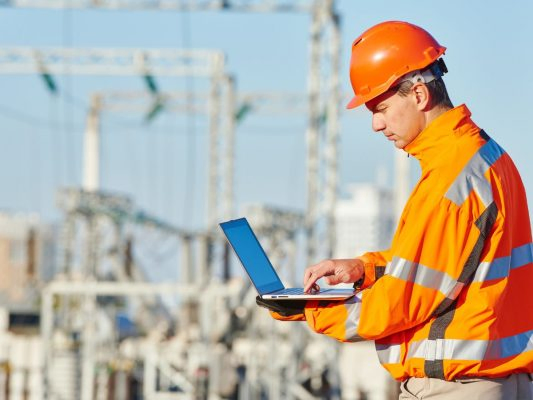 Pracownik budowy korzystający z systemu SyKOF HR na laptopie w terenie